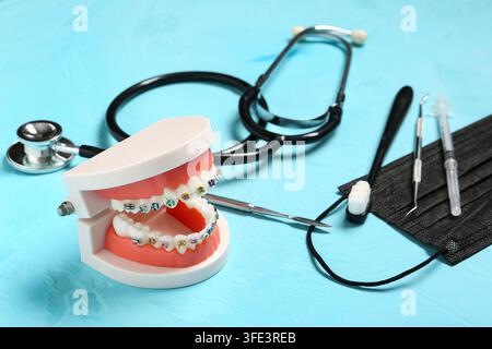 Orthodontics and dental health, model of teeth with colorful braces and medical tools for oral hygiene and professional care on a blue background Stock Photo