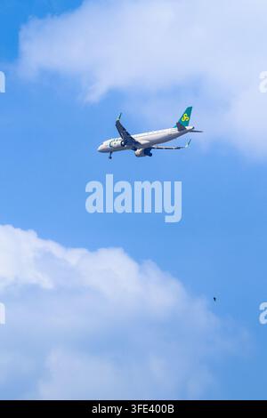 BANGKOK, THAILAND - MARCH 28, 2026: A Spring Airlines Airbus jet descends with landing gear extended over the city skyline. Stock Photo