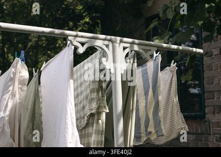 Fresh Laundry Drying on Ornate Victorian or Scandinavian Grey T-bar Clothesline in Sunlight. Vintage Outdoor Home Setting with Natural Fabrics Stock Photo