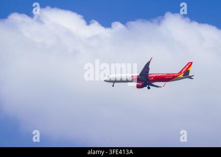 BANGKOK, THAILAND - MARCH 28, 2026: A Vietjet Air Airbus A321 jet in red livery descends with landing gear extended over the city. Stock Photo