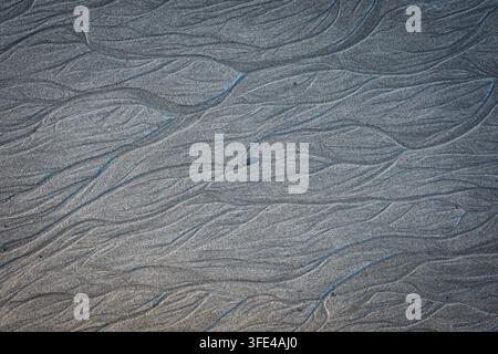 Natural abstract pattern of water channels carved in wet beach sand Stock Photo
