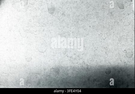 Close-up of a weathered, dirty, and scratched silver metal sheet texture with visible water stains, dust, and a dark shadow gradient at the bottom Stock Photo