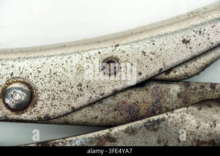 A detailed macro shot showing the rusty, pitted metal texture and rivets of an old pair of locking pliers Stock Photo