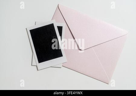 Minimalist top view of a shimmering pink envelope and two blank instant film frames, perfect for messages, memories, or invitation concepts Stock Photo