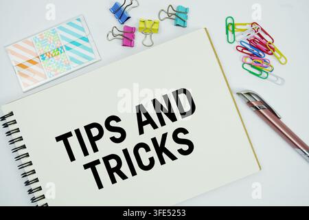 Tips And Tricks text message written on notepad with stationery flat lay on white background Stock Photo