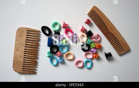 Two wooden combs are placed on a table along with various hair accessories. The accessories include colorful hair ties and clips arranged in a random Stock Photo
