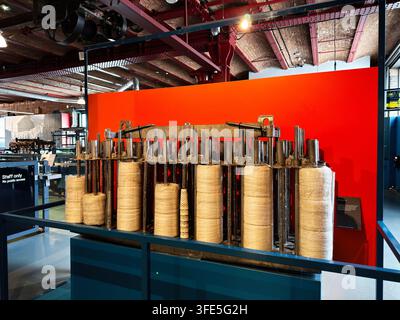Manchester, UK - July 02, 2026: Exhibit of a large spinning machine with stacked yarn bobbins and metal framework in Manchester museum. Stock Photo
