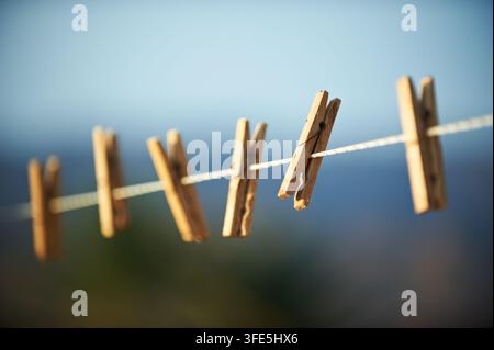 Row of vintage wooden clothespins clipped on a laundry line outdoors. Selective focus shot showcasing household, drying clothes, sustainable living, a Stock Photo