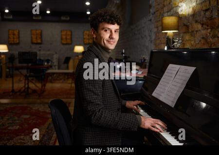 Man playing piano. Focused musician rehearsing with warm ambient lighting Stock Photo