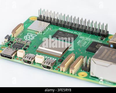 Macro shot focusing on Raspberry Pi 5 main CPU processor and microchips on green printed circuit board with shallow depth of field on bright backdrop Stock Photo