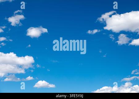 Sky background with fluffy white clouds on a bright blue sky Stock Photo