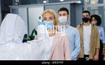 Protection Masks Example A health workers checks the temperature of a man before administering a ...