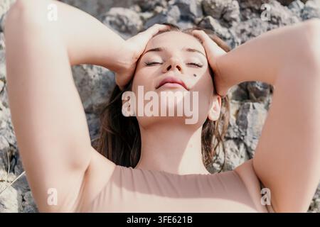 Woman relaxation nature serene young woman lying on rocks with eyes closed and hands on head in sunlight Stock Photo