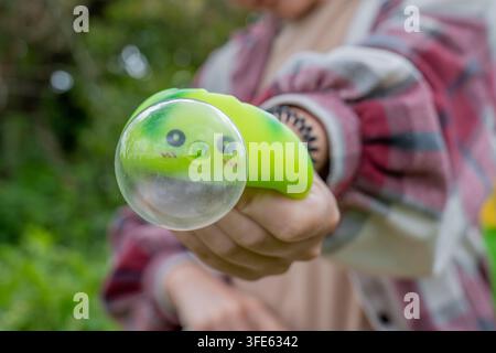 Person holding a green anti stress squishy toy with a giant popped bubble forward to the camera. Trendy fidget toys and stress management concept. Hig Stock Photo