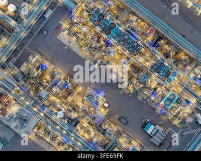 Aerial view of an industrial chemical plant at night with illuminated pipes, cooling fans, and storage tanks in Bantzenheim, Grand Est, France. Stock Photo