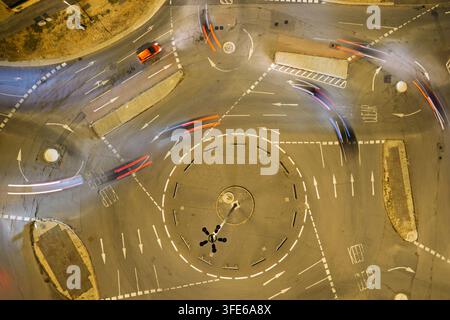 Aerial view of a roundabout at night with light trails from moving vehicles on the asphalt road in the United Kingdom. Stock Photo