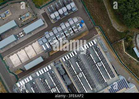 Aerial view of a modern data center featuring rows of cooling units, server infrastructure, and industrial equipment within a secure fenced perimeter Stock Photo