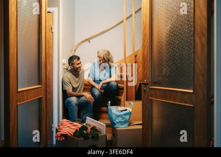 Happy couple sitting on stairs and talking in their new apartment Stock Photo