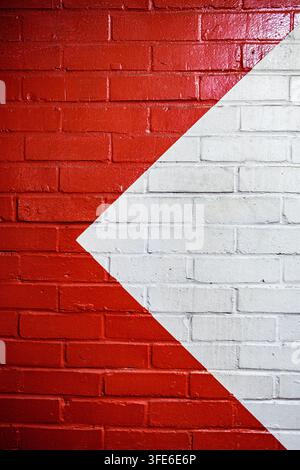 London, UK, August 31 2026, Close Up Of A Bright Red Painted Brick Wall With A Painted White Triangle Offset To The Right With Copy Space Stock Photo