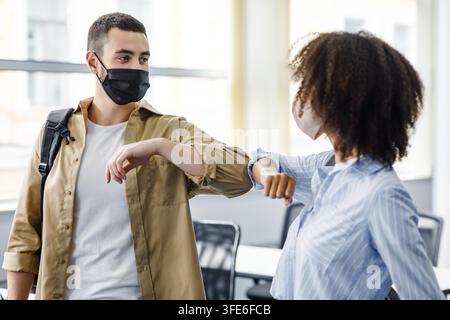 Arabian young man and african american woman greet each other in morning in interior of modern office Stock Photo