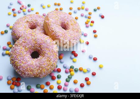 Pink doughnuts and candies on blue background, copy space flat lay Stock Photo