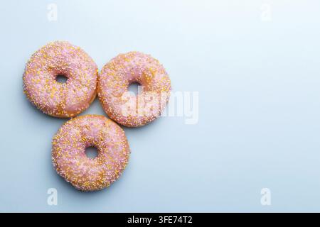 Pink doughnuts and candies on blue background, copy space flat lay Stock Photo