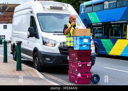London, UK, September 03 2026, Delivery Driver Stacking Plastic Crates On A Trolley For High Street Shop Deliveries Stock Photo