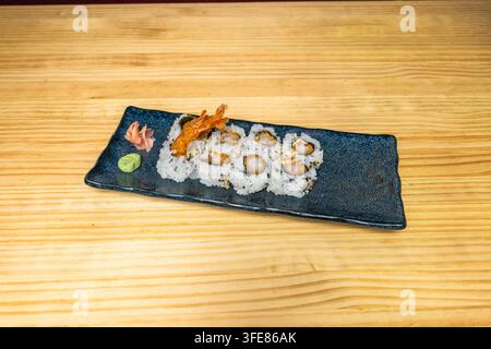 Crispy shrimp tempura uramaki rolls with sesame seeds, served on dark plate with ginger and wasabi. Stock Photo