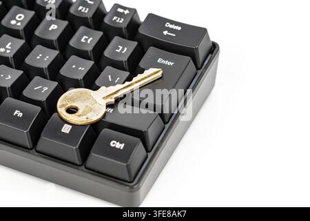 A gold key lies on a black keyboard's enter button, symbolizing cybersecurity and digital access permissions. Stock Photo