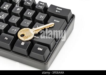 Antique gold key on a black keyboard's enter button, symbolizing internet security and digital access protection. Stock Photo