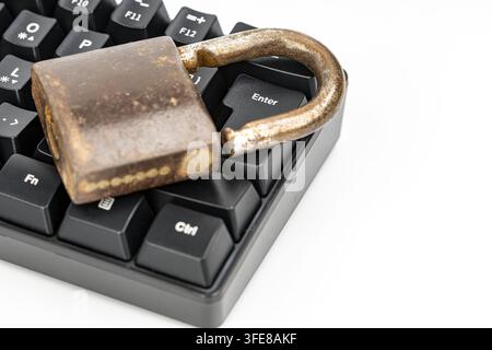 Rusty unlocked padlock on a computer keyboard near enter key, symbolizing cybersecurity and online data risks. Stock Photo