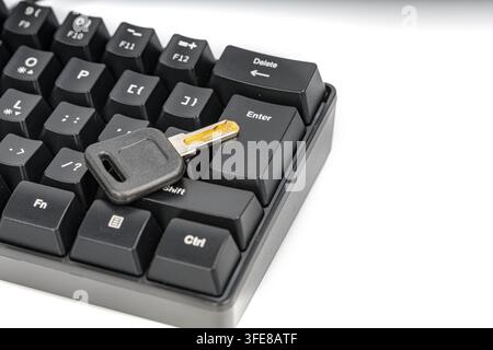 A metal key on the enter key of a black keyboard symbolizes digital security, access, and the consequences of confirming an action online. Stock Photo