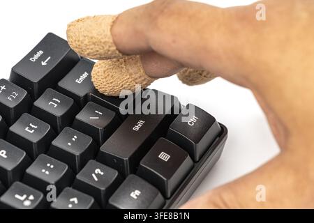 Bandaged fingers press enter on a keyboard, symbolizing the hidden risks and consequences of a single button press. Stock Photo