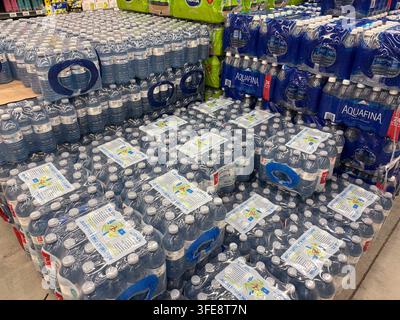 Water in plastic bottles stacked in large quantities inside a retail supermarket aisle display. Stock Photo