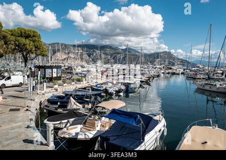 A large marina filled with numerous sailboats and motorboats under a bright blue sky with fluffy white clouds Stock Photo