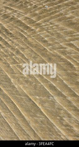 Close up of wavy golden sand dunes pattern and texture created by sea or ocean waves on coast in natural sunlight Stock Photo
