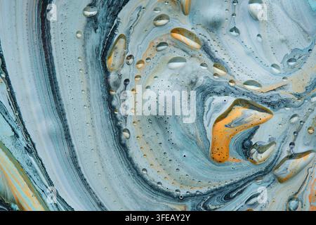 Swirling acrylic paint macro texture with blue, yellow, and grey colors covered in small water drops Stock Photo