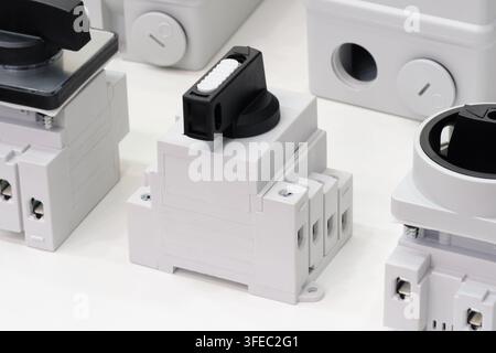 White plastic electrical relays with black knobs. Each unit has mounting screws and terminal sockets. They arranged on neutral background. Industrial Stock Photo