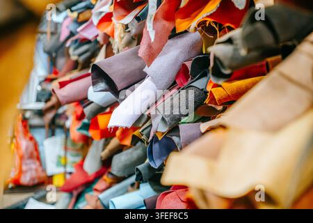 Rolled pieces of colorful leather and fabric are stacked together among handmade crafting materials. Stock Photo