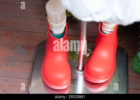 Mannequin legs wearing eye-catching red rubber boots, showcasing modern street style fashion Stock Photo