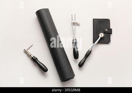 Leathercraft and artisan hobby, professional leather working tools with black leather roll and handmade wallet on a textured white background Stock Photo