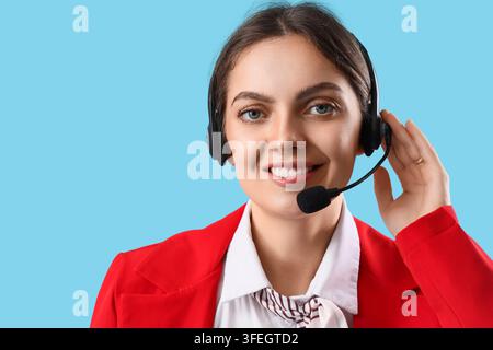 Customer support and help desk service, smiling female operator with headset providing professional assistance in a call center on a blue background Stock Photo