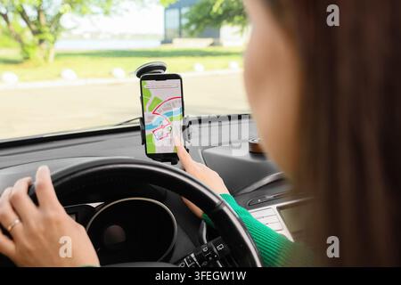 Navigation and route planning, woman driver using smartphone gps map on car dashboard mount for travel and commute guidance in vehicle Stock Photo