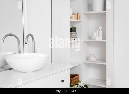 Interior of light bathroom with sink and shelf unit Stock Photo