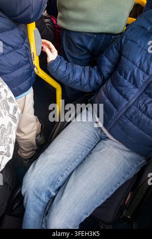 Disabled wheelchair / wheel chair user on a bus pressing the bell button to request leave / alight from the bus at the next stop. Twickenham, London. UK.(147) Stock Photo