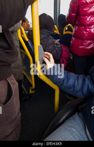 Disabled wheelchair / wheel chair user on a bus pressing the bell button to request leave / alight from the bus at the next stop. Twickenham, London. UK.(147) Stock Photo