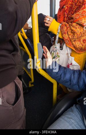 Disabled wheelchair / wheel chair user on a bus pressing the bell button to request leave / alight from the bus at the next stop. Twickenham, London. UK.(147) Stock Photo