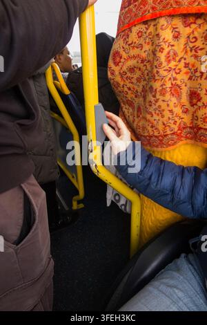 Disabled wheelchair / wheel chair user on a bus pressing the bell button to request leave / alight from the bus at the next stop. Twickenham, London. UK.(147) Stock Photo