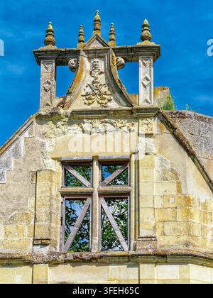 Stone facade of the historic Chateau de la Mothe Chandeniers in Nouvelle Aquitaine, France, featuring intricate reliefs and boarded window Stock Photo