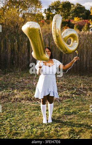 Happy young woman celebrating sixteenth birthday with balloons Stock Photo